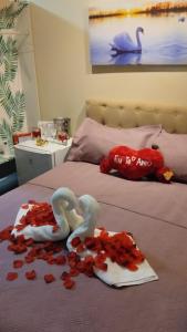 Pousada Cristais SUITE 15 في تيوفيلو أوتوني: يوجد بجعتين من بتلات الورد على السرير