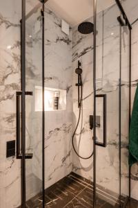 y baño con ducha y paredes de mármol blanco. en Beautiful Designer Apartment in Riga center en Riga