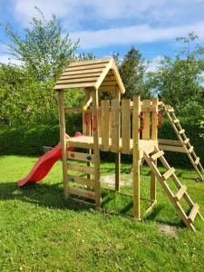 a wooden playground with a slide and a play structure at Ferienwohnung Bockholm Appartement 1 - 8 in Glücksburg