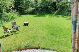 a backyard with a grill and a table and chairs at Reggies Hideaway a secluded off grid Shepherds hut in Saint Hilary +2 photos