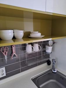 a kitchen counter with dishes on a shelf above a sink at Joongmoon ocean stay in Seogwipo