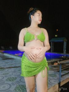 une femme en bikini vert debout à côté d'une piscine dans l'établissement Tam Coc Cat Luong Homestay, à Ninh Binh