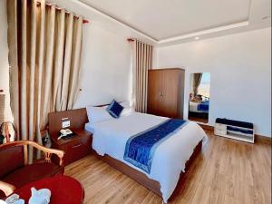 ein Hotelzimmer mit einem großen Bett und einem Stuhl in der Unterkunft Cosy Hotel & Apartment Dalat in Da Lat