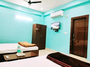 a blue room with two beds and a tv at Hotel Ambika in Deoghar