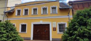 a yellow house with a brown door and windows at Hubertus Panzió in Csongrád