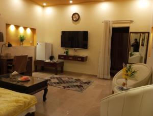 a living room with a couch and a tv at Hotel Luxe Heights Lahore in Lahore