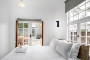 1 dormitorio blanco con 1 cama grande con almohadas blancas en Balmain Beauty - Spacious Garden en Sídney