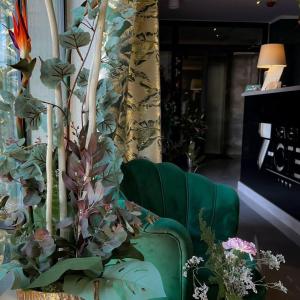 einen grünen Stuhl und eine Pflanze in einem Raum in der Unterkunft Seven Hotel Bytom - Katowice in Bytom