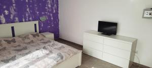 um quarto com uma cama e uma televisão numa cómoda em Guest House Ofilovi em Nesebar