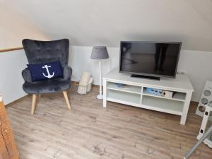 uma sala de estar com uma televisão e uma cadeira em Nordseeperle em Hage