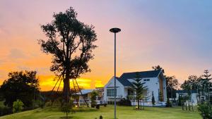 a house with a street light in front of a sunset at บ้านไร่ฟ้าสวย Family House in Ban Khlong Ta Sang