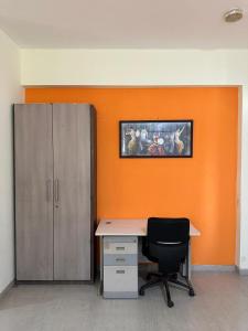 an office with an orange wall with a desk and a chair at Tapovan Villa & Resort in Pune
