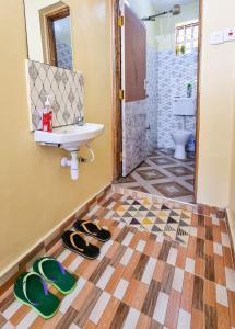 La salle de bains est pourvue d'un lavabo et d'une paire de chaussons. dans l'établissement Lovely 1 Bedroom Fully Furnished Nakuru, à Nakuru