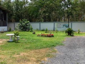un parc avec un banc et des fleurs dans l'herbe dans l'établissement KHUN CHUAT'S HOUSE, à Ban Nong Ben