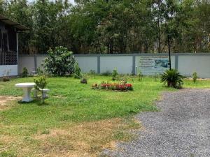 um parque com um banco e flores na relva em KHUN CHUAT'S HOUSE em Ban Nong Ben