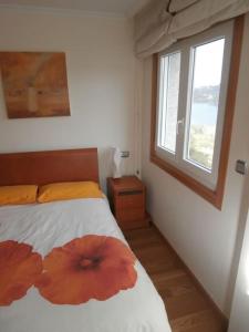 een slaapkamer met een bed met 2 bloemen erop bij Precioso apartamento con excelentes vistas al mar in Puentedeume