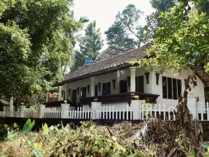 a white house with a white fence and trees at Sanctuary View Homestay Thattekad in Cochin