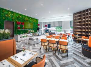 restauracja ze stołami i krzesłami oraz zieloną ścianą w obiekcie Hotel Mi Rochor w Singapurze