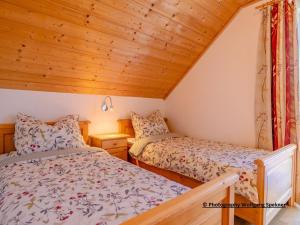2 Betten in einem kleinen Zimmer mit Holzdecken in der Unterkunft Chalet in Carinthia with Sauna near Ski Slopes in Weinebene