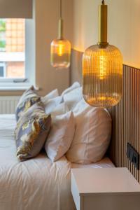 1 cama blanca con almohadas y 2 lámparas. en B&B Dijkhuis en Vrouwenpolder