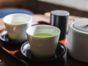Asakusa View Hotel Annex Rokku في طوكيو: كوبين من الشاي الأخضر على طاولة خشبية