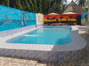 a swimming pool at a resort with a mural at Precious Holiday Homes Diani beach in Diani Beach