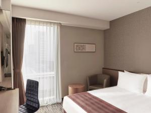 Habitación de hotel con cama y ventana en The Strings Hotel Nagoya, en Nagoya