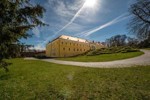 a large yellow building on a grassy field next to a road at Hotel Belcredi in Brno