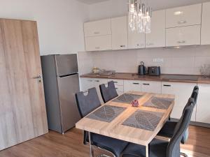 eine Küche mit einem Holztisch mit Stühlen und einem Kühlschrank in der Unterkunft Apartmany Rubin Nesvady in Nesvady
