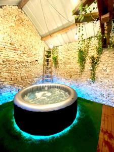 a hot tub in a room with a stone wall at Les maisons des Frangines 