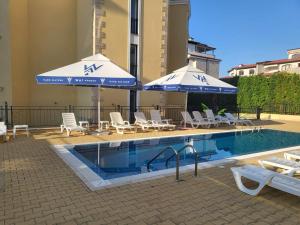 a swimming pool with umbrellas and chairs and a swimming pool at Horizon Katrina Apartments - Sea line & Beach Access in Sveti Vlas