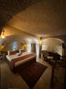 Ortahisarにあるオルタヒサル ケーブ ホテルの石造りの部屋に大型ベッドが備わるベッドルーム1室