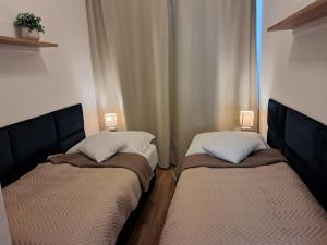 two beds in a small room with two lamps at Apartmany Rubin Nesvady in Nesvady