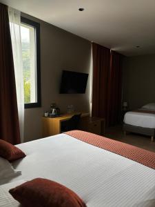 una camera d'albergo con letto e TV di LE CASTEL D'ALTI a Luchon
