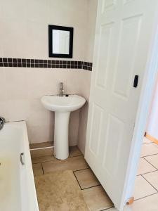 a bathroom with a sink and a white door at Frere Hill Guesthouse in Durban