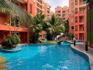 a swimming pool in a resort with palm trees and buildings at Seven Seas Condo Resort Jomtien in Jomtien Beach