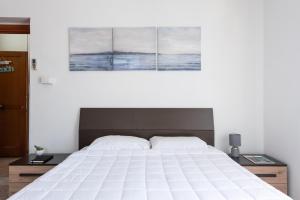 um quarto com uma grande cama branca com três pinturas na parede em 22 Passi dal mare( Parcheggio privato + wifi) em Francavilla al Mare