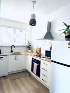 a kitchen with white cabinets and a white refrigerator at Studio on Lewis Tiny House in Mudgee