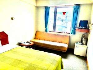 石垣島にあるホテルハッピーホリデー石垣島 のベッド、ソファ、窓が備わるホテルルームです。