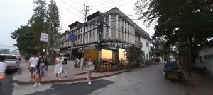 a group of people walking down a street in front of a building at MK Hostel in Luang Prabang