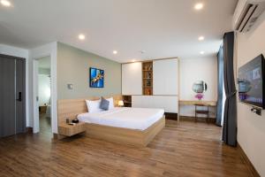 a bedroom with a large white bed and a desk at FIRST Studio Hotel in Danang