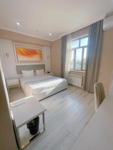 een slaapkamer met een bed, een tafel en een raam bij Moffah Grand Hotel 美华酒店 in Tasjkent