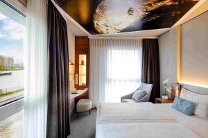 a hotel room with a bed and a desk and a window at Hey Lou Hotel Monheim am Rhein in Monheim +26 photos