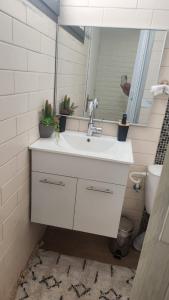 La salle de bains est pourvue d'un lavabo blanc et d'un miroir. dans l'établissement פינה קטנה בערבה, à Beʼer Ora