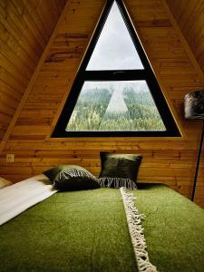 Bett in einem Zimmer mit einem großen Fenster in der Unterkunft Cozy chalet in Mestia in Mestia