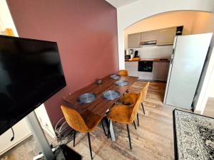 a dining room table with chairs and a flat screen tv at Suite Chanzy 69 in Reims
