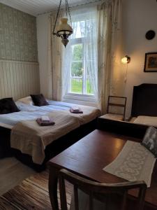 Zimmer mit 2 Betten, einem Tisch und einem Fenster in der Unterkunft Maalaishotelli Hanna&Magnus in Merikarvia