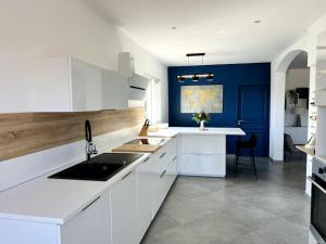 eine Küche mit weißen Schränken und einer blauen Wand in der Unterkunft Villa avec piscine et jacuzzi 3 min mer in Grosseto-Prugna