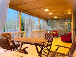 een afgeschermde veranda met een houten tafel en stoelen bij Teo's Cottages in Dedoplis Tskaro