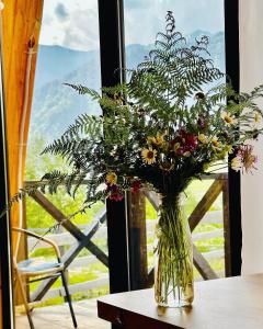 eine Vase mit Blumen auf einem Tisch vor einem Fenster in der Unterkunft Cozy chalet in Mestia in Mestia